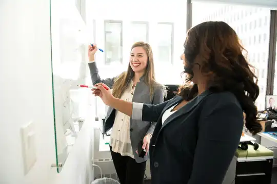 Two colleagues collaborating at a whiteboard in an office